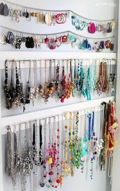 a white shelf filled with lots of different colored necklaces on it's sides