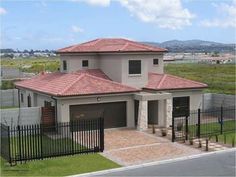 a house with a red tiled roof and black fence