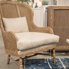 a wicker chair sitting on top of a blue rug next to a wooden table