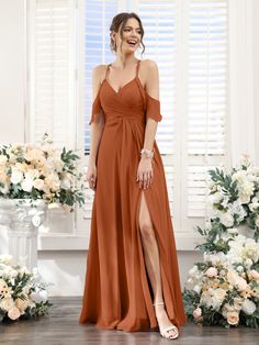 a woman standing in front of flowers wearing an orange bridesmaid dress with thigh high slit