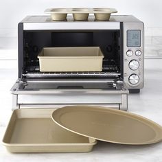 a toaster oven sitting on top of a counter next to pans and trays