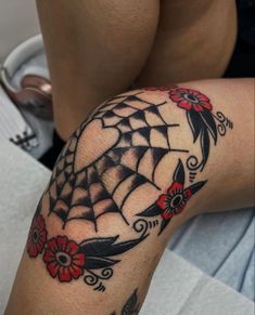 a woman's arm with a spider web tattoo on it and flowers in the center