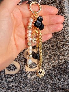 a person is holding a keychain with beads and charms attached to the chain