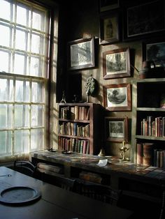 a room filled with lots of books and pictures on the wall next to a window