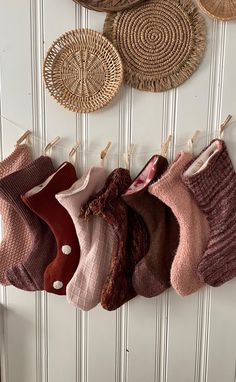 several pairs of socks hanging from clothes pins on a wall with wicker baskets above them