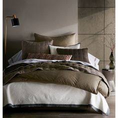 a bed with brown and white comforters in a room next to a lamp on the wall