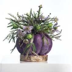 a purple vase filled with flowers on top of a white table