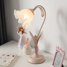 a lamp that is sitting on top of a desk next to a small bunny figurine