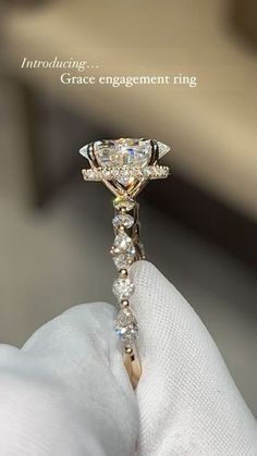 a close up of a person's hand holding an engagement ring