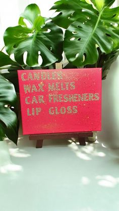 a red sign sitting on top of a table next to a green leafy plant