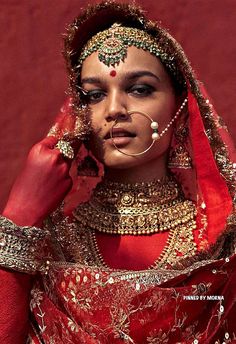 a woman dressed in red and gold is posing for the camera with her nose ring