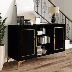 a black and gold sideboard in front of a stair case with books on it