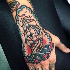 a man's hand with a ship tattoo on it