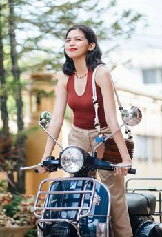 a woman standing next to a motorcycle with a basket on it's handlebars