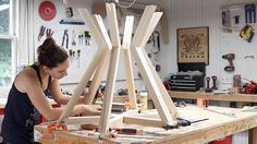 a woman sitting at a workbench working on some woodworking pieces in her workshop