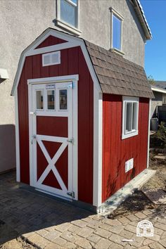 a small red and white barn with windows