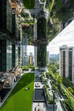 an aerial view of a city with tall buildings and greenery in the foreground