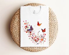 Embrace nature with this adorable floral butterflies t-shirt! Featuring a beautiful design of colorful flowers and vibrant butterflies, this cute t-shirt is perfect for women who love nature and animals. Made from soft, high-quality fabric, this t-shirt offers comfort and style for any casual occasion. The image on this t-shirt was created with artificial intelligence. This classic unisex jersey short sleeve tee fits like a well-loved favorite. Soft cotton and quality print make users fall in lo Cute Butterfly Print T-shirt For Spring, White Butterfly T-shirt For Summer, White Butterfly T-shirt For Spring, Multicolor Tops For Spring As A Gift, Cute Spring Butterfly Print T-shirt, Multicolor Short Sleeve T-shirt With Butterfly Print, Floral Print T-shirt For Spring Gift, Floral Print T-shirt As A Spring Gift, Floral Print T-shirt For Spring