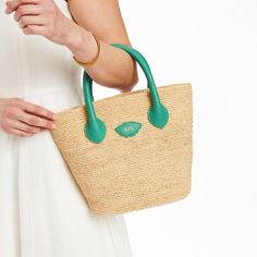 Inspired by a recent trip to Italy, the Mia Handbag is a beautiful bag for summer days, wedding celebrations or any time you need a touch of luxury. Its beauty is in its simplicity: handwoven raffia meets soft and supple Italian leather. This unlined open tote instantly evokes long summer days on the Italian countryside. Add a foil debossed monogram for a personal touch.    7.5"w (bottom), 13.5"w (top) x 4.75"d x 10"h  Handle drop: 4"  Handwoven raffia, Italian leather.  Clean with a soft cloth. Elegant Handwoven Bucket Bag For Travel, Elegant Handwoven Travel Bucket Bag, Summer Beach Bag With Detachable Handle In Natural Color, Elegant Handwoven Natural Bucket Bag, Chic Crochet Top Handle Bag With Rolled Handles, Elegant Natural Bags With Handles, Chic Straw Basket Bag With Rolled Handles, Chic Basket Straw Bag With Rolled Handles, Natural Straw Bag With Detachable Handle For Summer