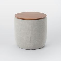 a round ottoman with a wooden top and grey fabric cover, on a white background