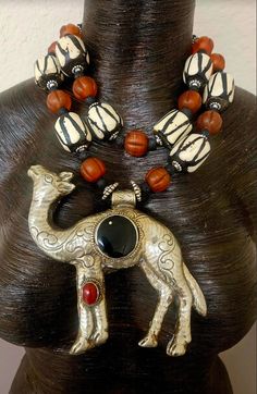 This rare and scarce tribal statement necklace is new and unworn from my private collection. It features a very hard to find Tibetan Repousse Camel pendant with inlaid black onyx and red carnelian. I remain uncertain about the small gold metal spor at the 11 o'clock position in the onyx, but I purchased the stone like this. The camel is as ornate on the back as it is on the front, and measures a lightweight 5.25" x 5" (the camel is hollow). The adjustable double strand beaded necklace ranges fro Artisan Black Ceremonial Jewelry, Black Bohemian Necklace For Ceremonial Occasion, Artisan Carved Black Necklace, Artisan Black Carved Necklace, Traditional Black Necklaces With Large Pendant, Traditional Black Necklace With Large Pendant, Artisan Black Jewelry For Festivals, Bohemian Black Carved Necklace, Jewellery Shop Design