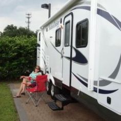 a woman sitting in a chair next to an rv