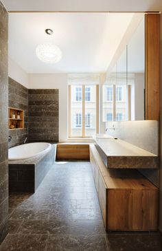 a large bathroom with stone walls and flooring, along with a tub in the corner