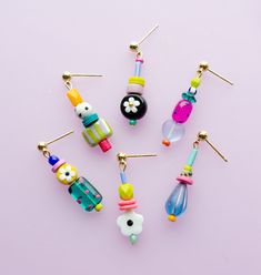 six different colored glass bead earrings on a pink background