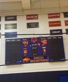 the scoreboard is hanging on the wall in front of the basketball court's numbers