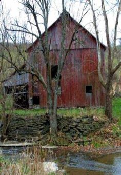 an old red barn sitting next to a river