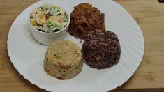 four different types of food on a white plate next to a bowl of coleslaw