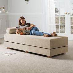 a woman sitting on a couch reading a book