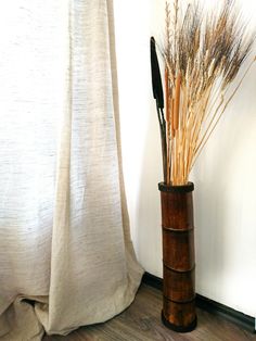 a tall wooden vase with dried plants in it