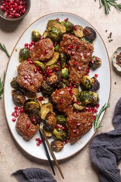 a white plate topped with meat and veggies covered in pomegranate