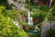 the waterfall is surrounded by lush green trees and water flowing down it's sides