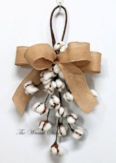 a bunch of cotton hanging from a brown ribbon on a white wall with a bow