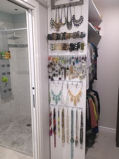 a white closet with lots of necklaces hanging from it's walls and doors