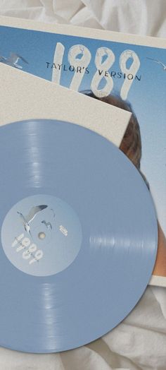 a blue record sitting on top of a bed next to a book and remote control