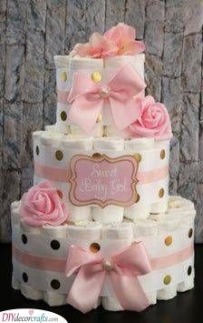 a three tiered baby shower cake with pink and gold polka dots on the bottom