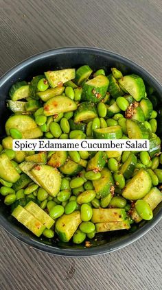 a black bowl filled with green vegetables on top of a wooden table and the words spicy edamae cucumber salad