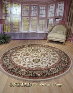 a large round rug is in the middle of a room with two chairs and windows