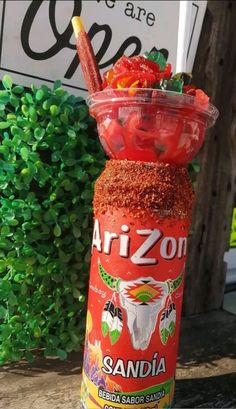 a jar filled with lots of food sitting on top of a wooden table next to a bush