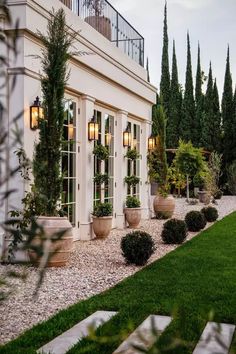 a white house with lots of windows and potted plants in front of the door