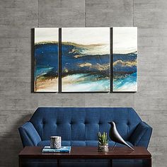 a living room with blue couches and two paintings on the wall above each sofa