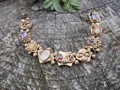 Set in 14k yellow gold, this enchanting multi stone slide bracelet dates from the 1940's. Each of the 9 charming slides are unique.  They include  pearl, amethyst, enamel, garnet,  opal  and sapphire, creating a story of its own.  It  comes together for an energetic look draped in magnificence.   The bracelet measures 8 1/8" long.  It measures 1/2" wide.  The bracelet weighs 51.70 grams. It is marked 14k.  BR 956 SIX MONTH LAYAWAY AVAILABLE Antique Gemstone Bracelet For Anniversary, Heirloom Gold Gemstone Bracelets, Elegant Vintage Charm Bracelet For Anniversary, Heirloom Style Formal Bracelets With Vintage Charm, Heirloom Bracelets With Vintage Charm For Formal Occasions, Gold Bracelets With Vintage Charm For Anniversary, Gold Bracelet With Vintage Charm For Anniversary, Elegant Vintage Charm Bracelets For Anniversary, Heirloom Style Gold Bracelets With Jewels