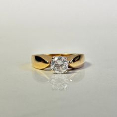 a yellow gold ring with a single diamond on the center and two black bands around it