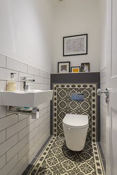 a white toilet sitting inside of a bathroom next to a wall mounted sink and mirror