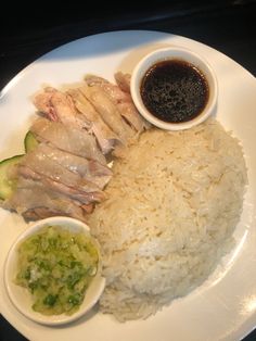 a white plate topped with rice and meat next to sauces on top of it