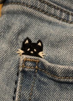 a small black and white cat sticking out of the back pocket of a pair of jeans