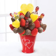 a red vase filled with assorted chocolate covered strawberries and heart shaped candies